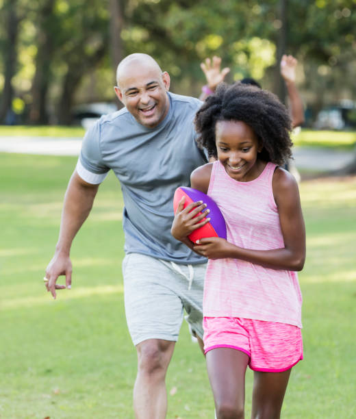 istock Girl and father playing with ball in park 1129643397