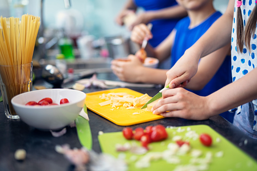 Close-up of hands of kids cooking meal. Kids are chopping and mixing ingredients for family lunch.
Nikon D850