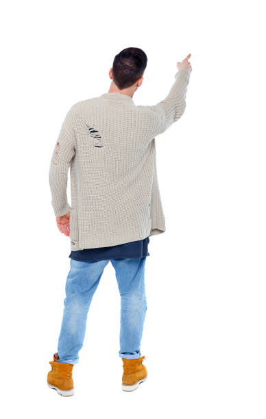 istock Back view of a stylish man in a knitted sweater points his hand 1129644927