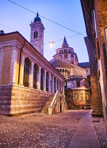 the fontanone visconteo with the basilica di santa maria maggiore in the background at nightfall. citta alta, bergamo, lombardy, italy. - religion christianity bell tower catholicism imagens e fotografias de stock