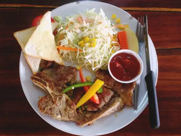 Photo of Pork steaks that are arranged in a plate, viewed from above.