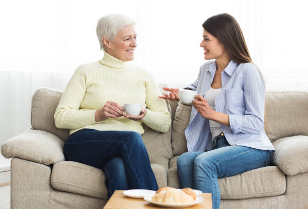 istock Happy mom and daughter talking and drinking tea 1129646579