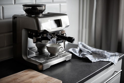 A combination of a modern and classic coffee machine with touch screen and portafilter in modern white and black kitchen. Selective focus.