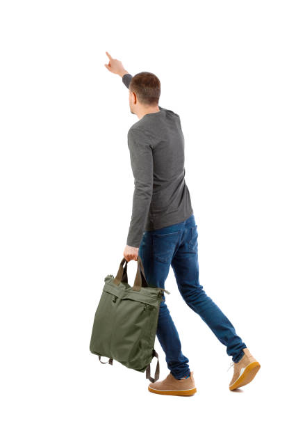 istock Back view of a walking man with a bag pointing his hand up. 1129646959
