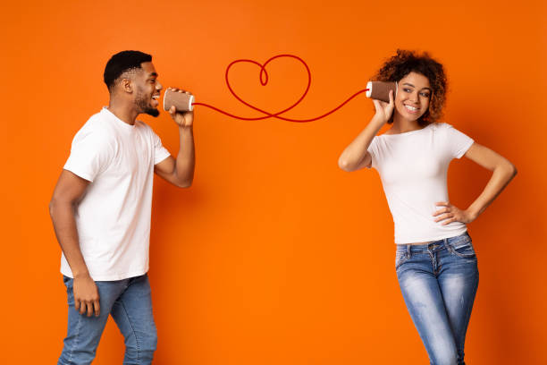 young black couple with can phone on orange background - couple indoors studio shot horizontal imagens e fotografias de stock