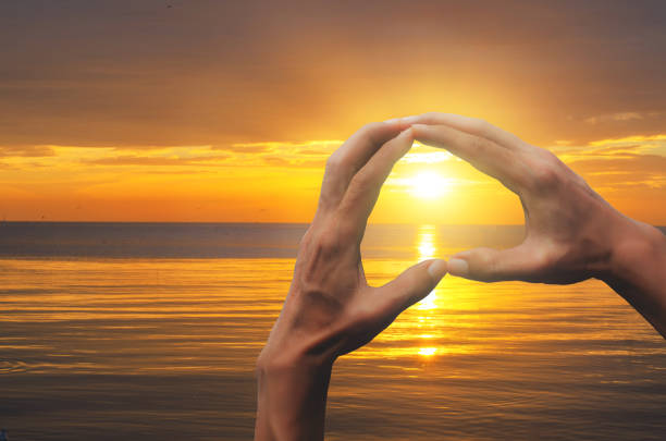istock silhouette heart love hand sign shape thru sunlight with sunset background on beach beautiful at outdoor romantic nature valentines day concept. 1129648121