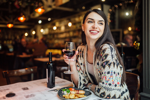 A woman smiling while drinking wine