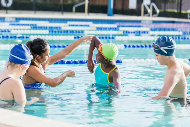 istock Young woman giving swim lessons to multi-ethnic group 1129649578