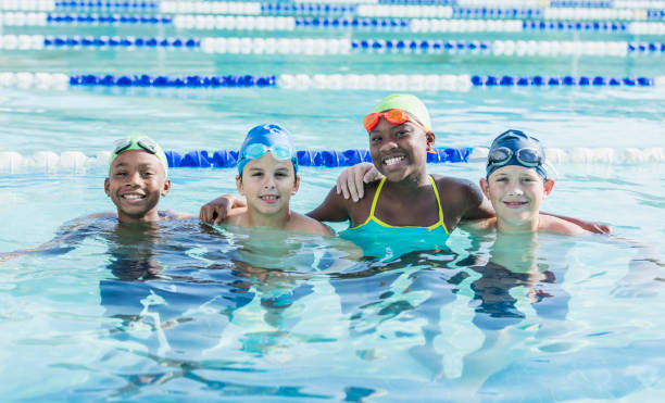 istock Multi-ethnic children in swimming pool smiling at camera 1129650023