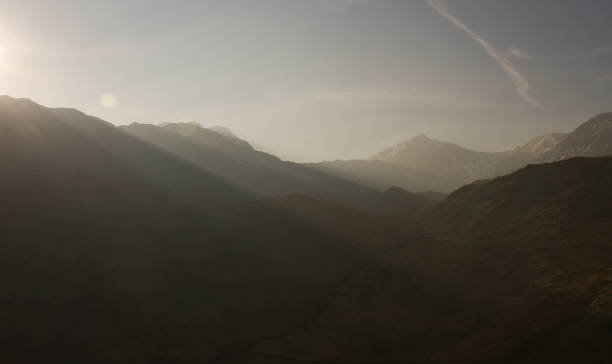 Mountain range with sunbeams Sunbeams breaking across a mountain range from the setting sun. llyn gwynant stock pictures, royalty-free photos & images