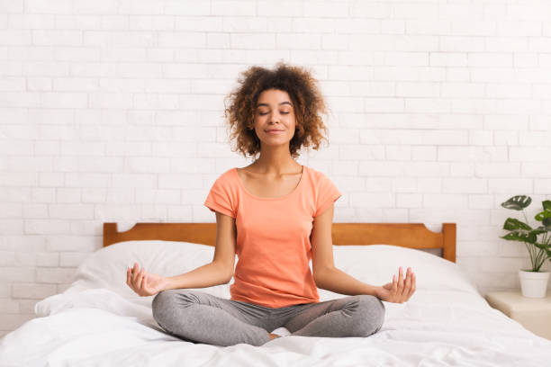 Meditation. Woman sitting in lotus pose on bed