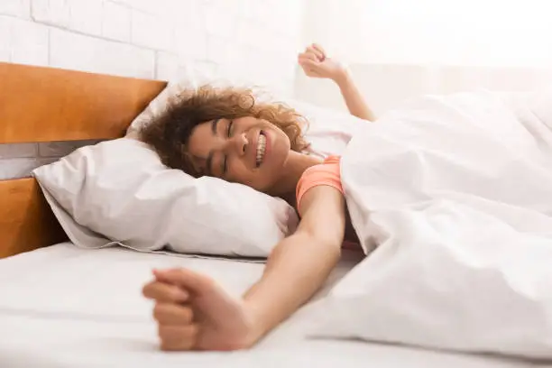 Photo of Happy woman waking up after sleep on bed