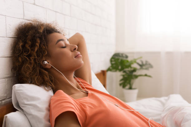 femme afro-américaine se détendre et écouter de la musique - female likeness audio photos et images de collection