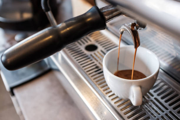 istock Espresso dripping from portafilter of coffee machine into white cup 1129651866