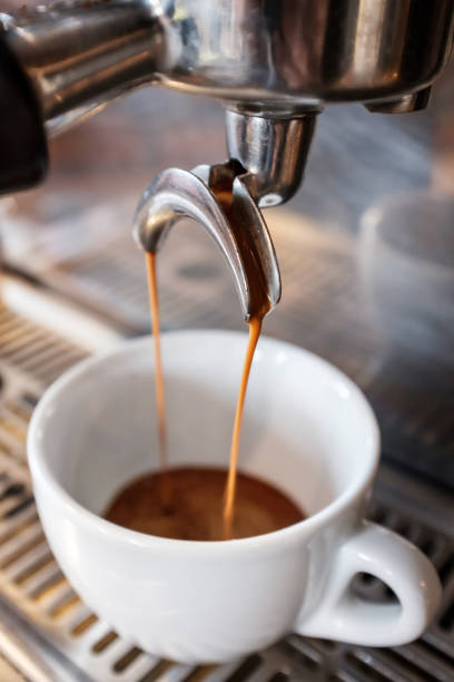 istock Espresso dripping from portafilter of coffee machine into white cup 1129651868