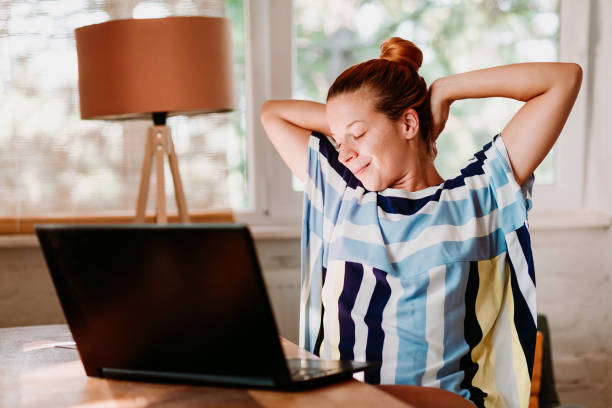 istock Young woman working on laptop stretching neck and arms 1129652681