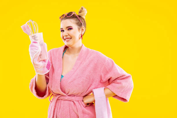 istock Wife wearing pink bathrobe smiling holding kitchen utensils 1129652857