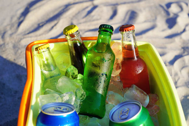 istock Soda drinks and filled ice cubes in a coolbox on the beach sand. 1129655563
