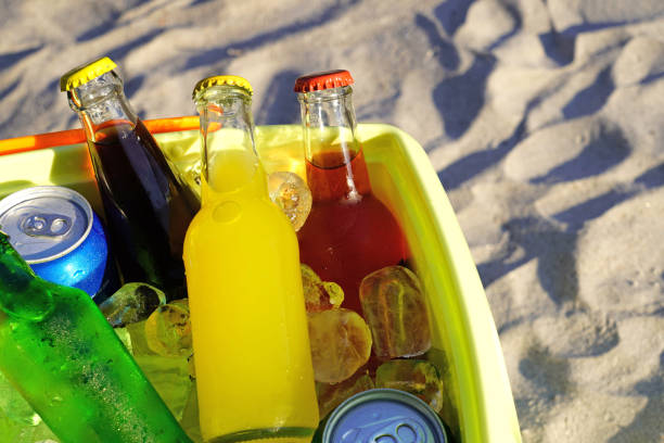 coloridas bebidas gaseosas y cubitos de hielo rellenos en una nevera en la arena de la playa. - raspberry soda fotografías e imágenes de stock