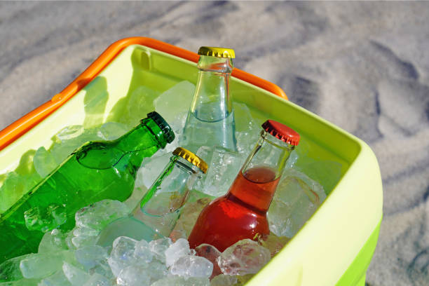 istock Glass bottle soda drinks and filled ice cubes in a coolbox on the beach sand. 1129655565