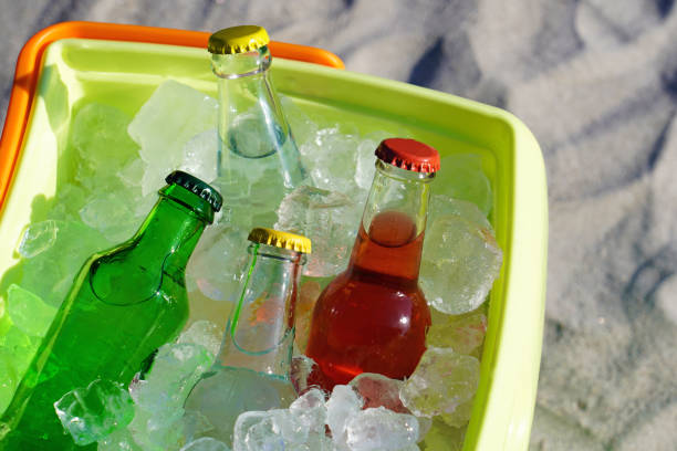 cristal botella soda bebidas y cubitos de hielo rellenas en una nevera en la arena de la playa. - raspberry soda fotografías e imágenes de stock