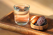 Date fruits in a wooden bowl and water in glass