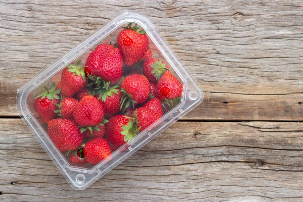 Fresh strawberry in plastic box on wooden table with copy space.