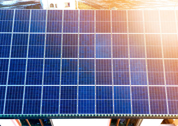 close-up surface of lit by sun blue shiny solar photo voltaic panels system on building roof. renewable ecological green energy production concept. - voltaic imagens e fotografias de stock