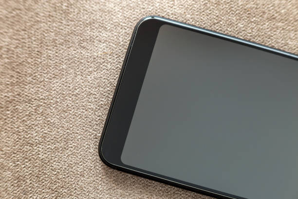istock New black modern cellphone isolated on light cloth copy space background. Modern technology, communication and gadget design concept. 1129656157