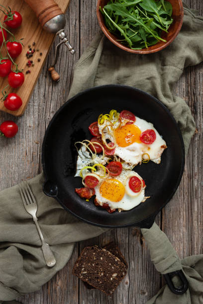 istock Pan with Fried eggs and cherry tomatoes on rustic background. Top view, close up, flatlay 1129656980