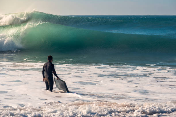 istock Surfer with board watches the waves from the shore 1129661576