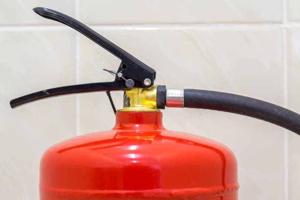 istock Fire extinguisher bright red isolated on white light tiles walls and floor copy space background. Danger and safety, fire protection concept. 1129661988