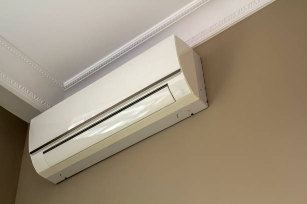istock Cool air conditioner installed in room interior on white ceiling and light walls copy space background. Climate control, comfortable home concept. 1129662075