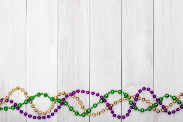 Mardi Gras beads on white wooden backgound