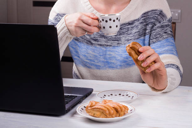 istock Women in the office drinking morning coffee with profiteroles. Coffeebreak during the working day. 1129663157