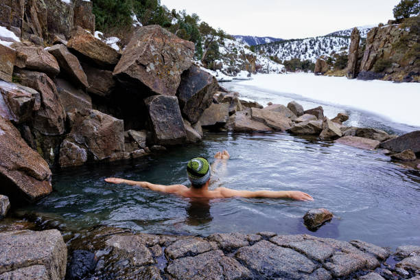 楽しんでリラックスした男はコロラド川に沿って、冬の天然温泉に浸る ストックフォト