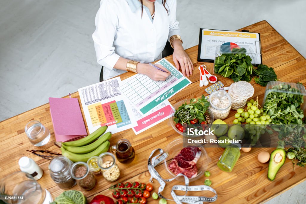 Rédiger un plan de régime alimentaire sur la table pleine de nourriture saine - Photo de Nutritionniste libre de droits
