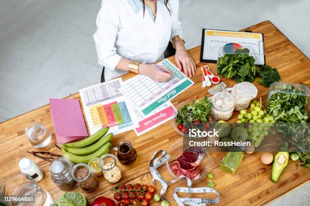 Photo libre de droit de Rédiger Un Plan De Régime Alimentaire Sur La Table Pleine De Nourriture Saine banque d'images et plus d'images libres de droit de Nutritionniste