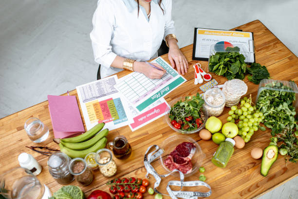 Writing a diet plan on the table full of healthy food Dietitian writing a diet plan, view from above on the table with different healthy products and drawings on the topic of healthy eating meal planning stock pictures, royalty-free photos & images