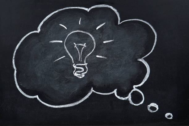 istock Chalk hand drawing idea bulb in thought bubble on blackboard 1129665272