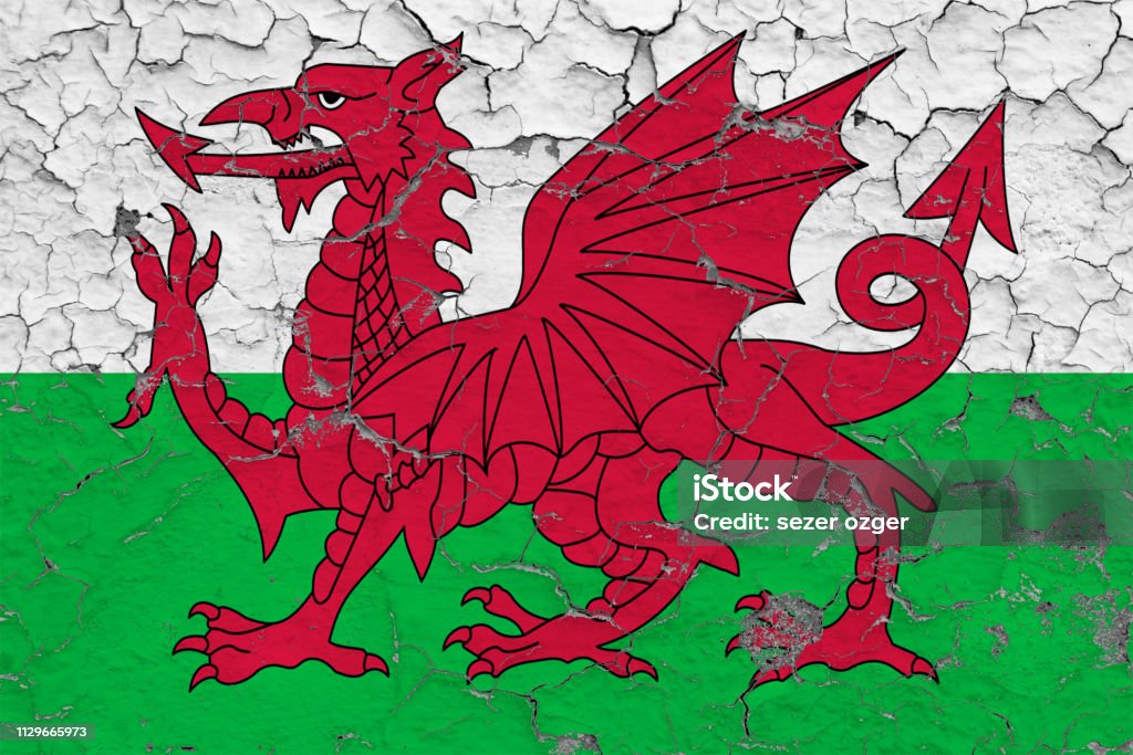 Flag of Wales painted on cracked dirty wall. National pattern on vintage style surface. Abstract Stock Photo