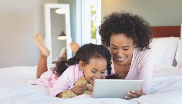 istock Happy African American mother and her daughter using digital tablet 1129668090