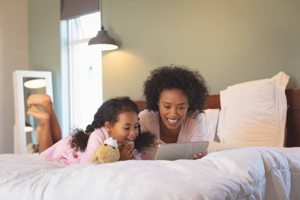 istock Happy African American mother and her daughter using digital tablet 1129668127