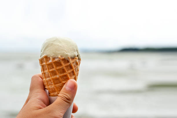 istock A hand holding a cone with vanilla ice cream 1129668130
