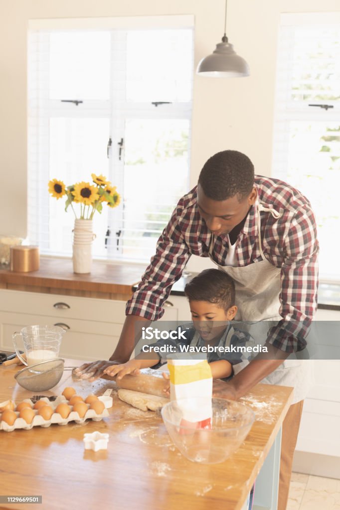 African American father and son rolling out cookie dough in kitchen Front view of African American father and son rolling out cookie dough in kitchen at home 30-39 Years Stock Photo