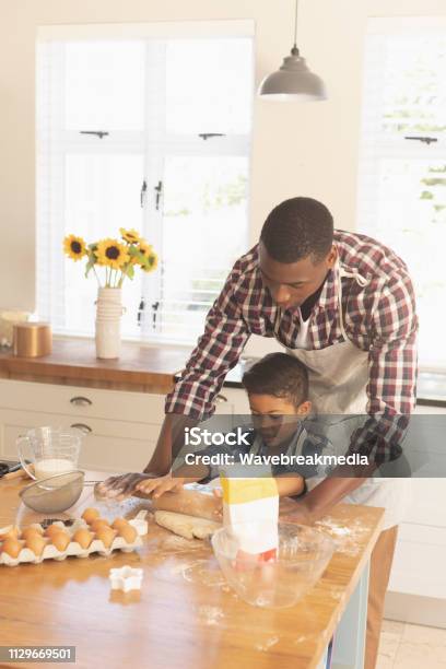 African American Father And Son Rolling Out Cookie Dough In Kitchen Stock Photo - Download Image Now