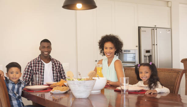 istock African American family sitting at dining table and looking at camera 1129669675