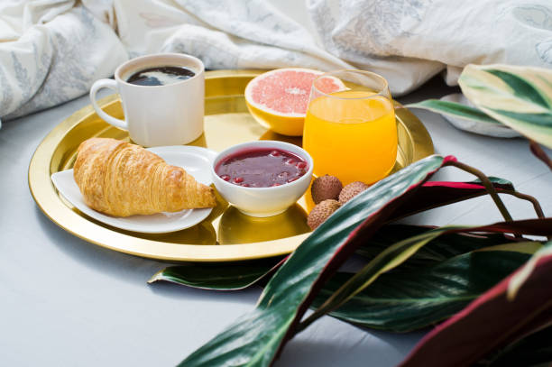 istock Classic Breakfast in bed, hotel service. Coffee, jam, croissant, orange juice, grapefruit, lychee. Side view 1129670915