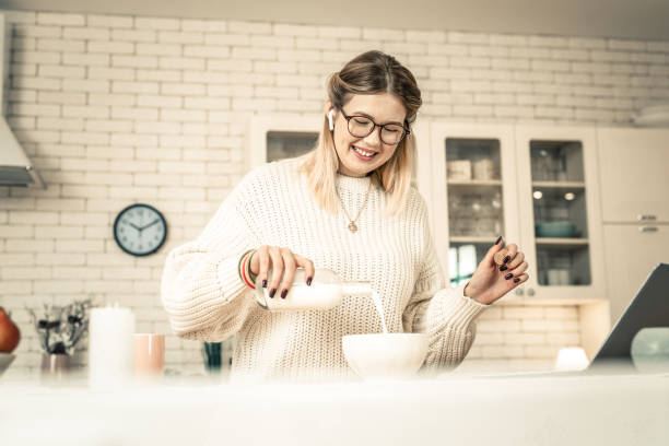 istock Beaming pretty lady pouring milk from glass bottle 1129672312