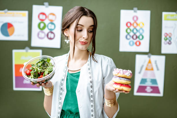 nutricionista com donuts e salada saudável - dietology - fotografias e filmes do acervo